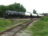 The conductor rides on an empty tank car.