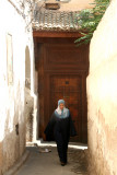 A Muslim woman walking in front of an ancient door in the medina in Fs.