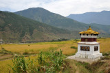 A stupa with prayer wheels set among the rice fields