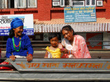 An old Nepali woman smiles as a little girl on a passing bus waves