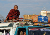 Monk riding on the roof of a packed MTU local bus, Mandalay