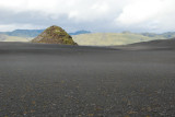 Green mountain on lava plain