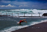 A young man dives into Avalon Rockpool on a winter's day