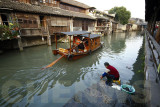 A woman washes her clothes in the water of the canal.