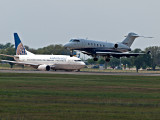 A Bombardier DD-100 landing in front of a continental airliner waiting for clearance. 