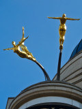 Three golden female statues diving from a roof above Piccadilly Circus