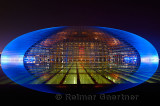 National Centre for the Performing Arts egg in blue light at night reflected in pool water Beijing China