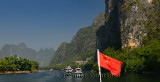 Chinese flag and cruise ships and sightseeing rafts on the Lijiang river Guangxi China with tall karst mountains