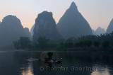 Cormorant fisherman on the Li river Yangshuo China with tall karst limestone peaks at dawn