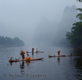 Cormorant fishermen in morning mist on the Li river with Karst mountain peaks near Xingping China
