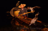 Cormorant fisherman holding bird on a pole on a bamboo raft on the Li river at night Huangbutan China