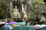 Limestone Buddha scultpures at Feilai Feng in the rain with umbrellas Ling Yin temple Hangzhou China