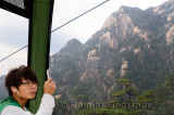 Young man taking a cellphone picture of Yellow Mountain from the Yungu cable car China