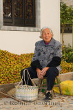 Portrait of old Chinese woman cracking shells of tung seeds in Chengkan China