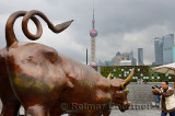 Tourist taking picture of the Bund bull with Shanghai skyline financial towers China