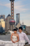 Wedding couple in white on the Bund with Pudong high rise towers Shanghai China