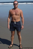 suntanned dad swimming trunks standing beach.jpg