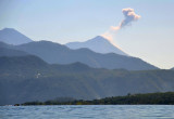 Volcn de Fuego, an active volcano to the east, blows off a puff of ash