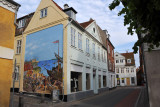 The mural is on the side of a building on Sankt Anna Gade near the church