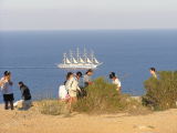 Visitors enthralled by the majesty of the worlds largest cutter as she quietly passes La Mola in evening sunlight