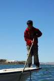 Crew member poling the boat alongside the pier