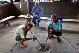 Lighting and smoking pipes in a Kam drum tower.