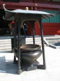Pot for incense sticks in front of a temple