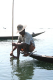 He is pushing down with his foot the conical, woven bamboo basket that they use for catching fish.