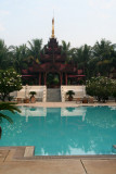 There is a mini pagoda-like structure behind the pool.