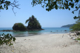 View of the Pacific Ocean and a rock with vegetation from Manuel Antonio beach.