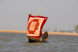 A small boat on the Niger with a colorful sail