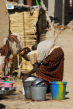 Woman washing dishes with sleeping baby