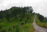 Paved road on the Thai side of the border with a dirt trail on the Myanmar side