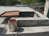 old paint bucket used with rope tied to it to dip water from the tank