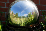 Refleting ball besides greenhouse.