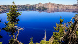 Wizard Island and the lake rim reflected in the deep blue water in Crater Lake National Park