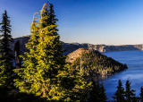 The light at sunset bathes the trees and Wizard Island in Crater Lake National Park