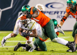 Tech A-back Perkins dives for extra yardage after being hit by Canes DL Olsen Pierre