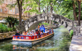 A tour boat cruises along the San Antonio River Walk