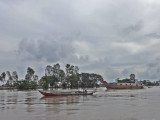 A sampan (foreground) on the Mekong River - in Vietnam while traveling by boat from Chau Doc, Vietnam to Phnom Penh, Cambodia