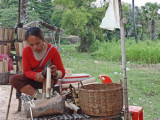 Woman at a food stand on the side of the road preparing sticky rice in bamboo