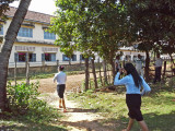 Several girls in their school uniforms going to the high school (background)