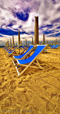 Blue beach chairs on golden beach, Italy