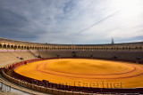Golden groomed sand and empty stands at the oval Seville bullfighting ring with Giralda tower
