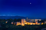 Moonrise over hilltop Alhambra Palace fortress complex at twilight Granada with Sierra Nevada Mountains