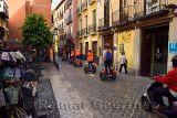 Line of bright orange Segway rider tourists on Elvira street Granada Spain