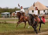 Kazakh horse riders galloping past with arms raised in Huns Village Kazakhstan