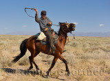Kazakh cowboy whipping horse on the plains of Zhongar Alatau mountains Kazakhstan
