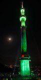 Green lights on Almaty TV tower on Kok Tobe mountain at night with moon Kazakhstan