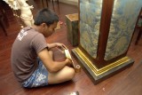 Retouching the base of the pillar with gold leaf